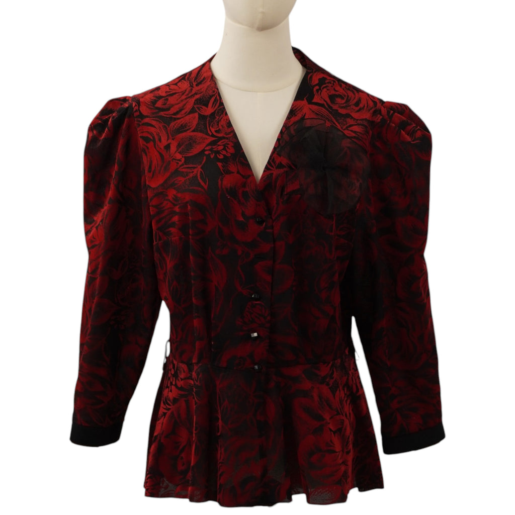 Vista frontale della blusa vintage nera con stampa di rose rosse, scollo a V, maniche a sbuffo e taglio peplum in vita.
