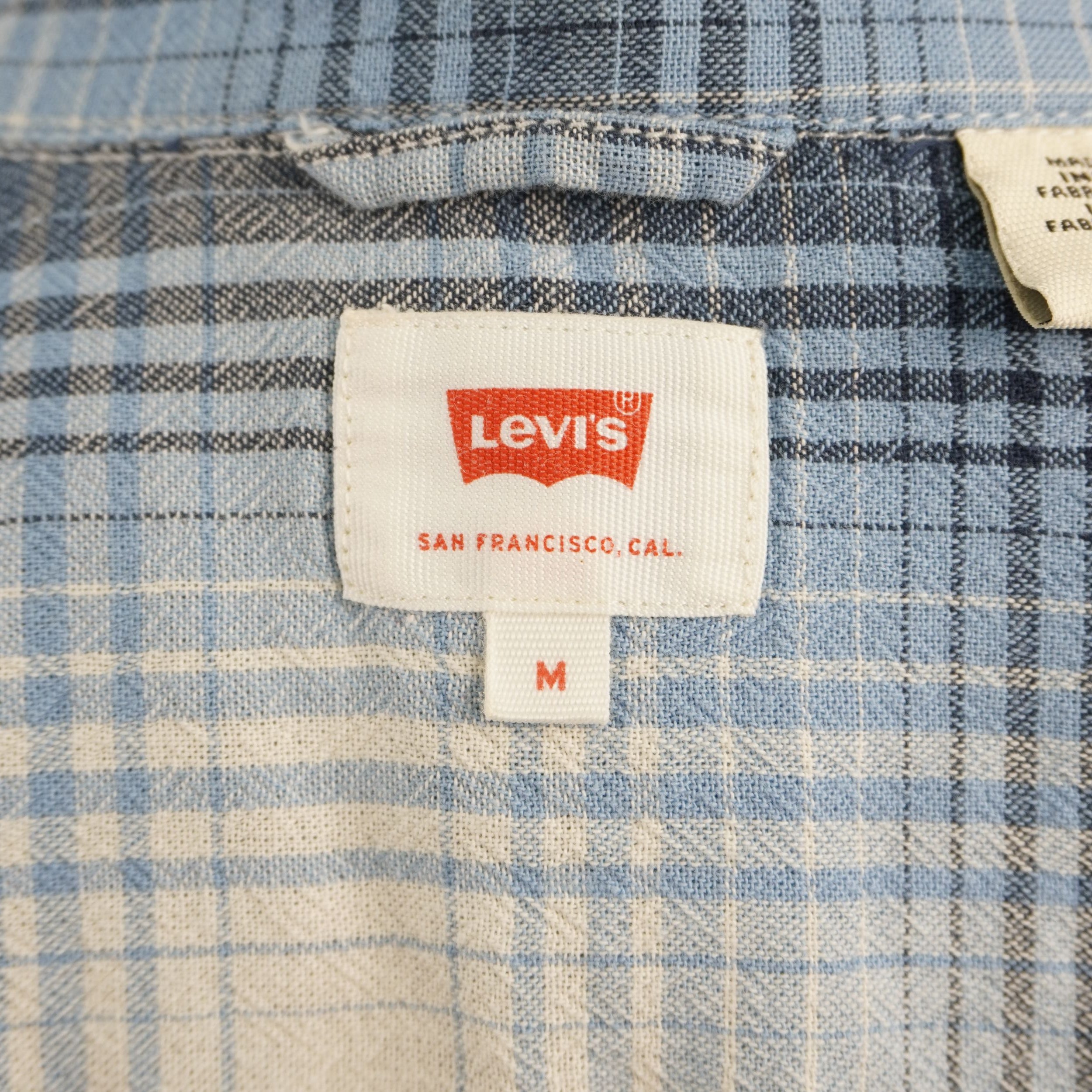 Camicia Levi's modello Western Pearl Snap a maniche corte, fantasia a quadri plaid azzurro, blu e beige. Dettaglio bottoni a pressione madreperla, taschini a punta e Red Tab originale. Taglia M in ottime condizioni vintage.
