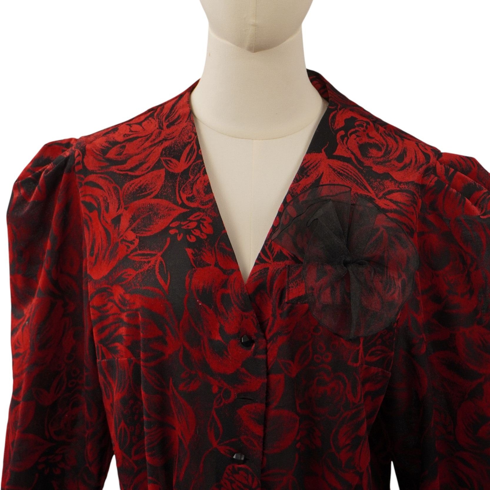 Primo piano della parte superiore della blusa con evidenza dello scollo a V profondo e del volume strutturato delle maniche a sbuffo.
