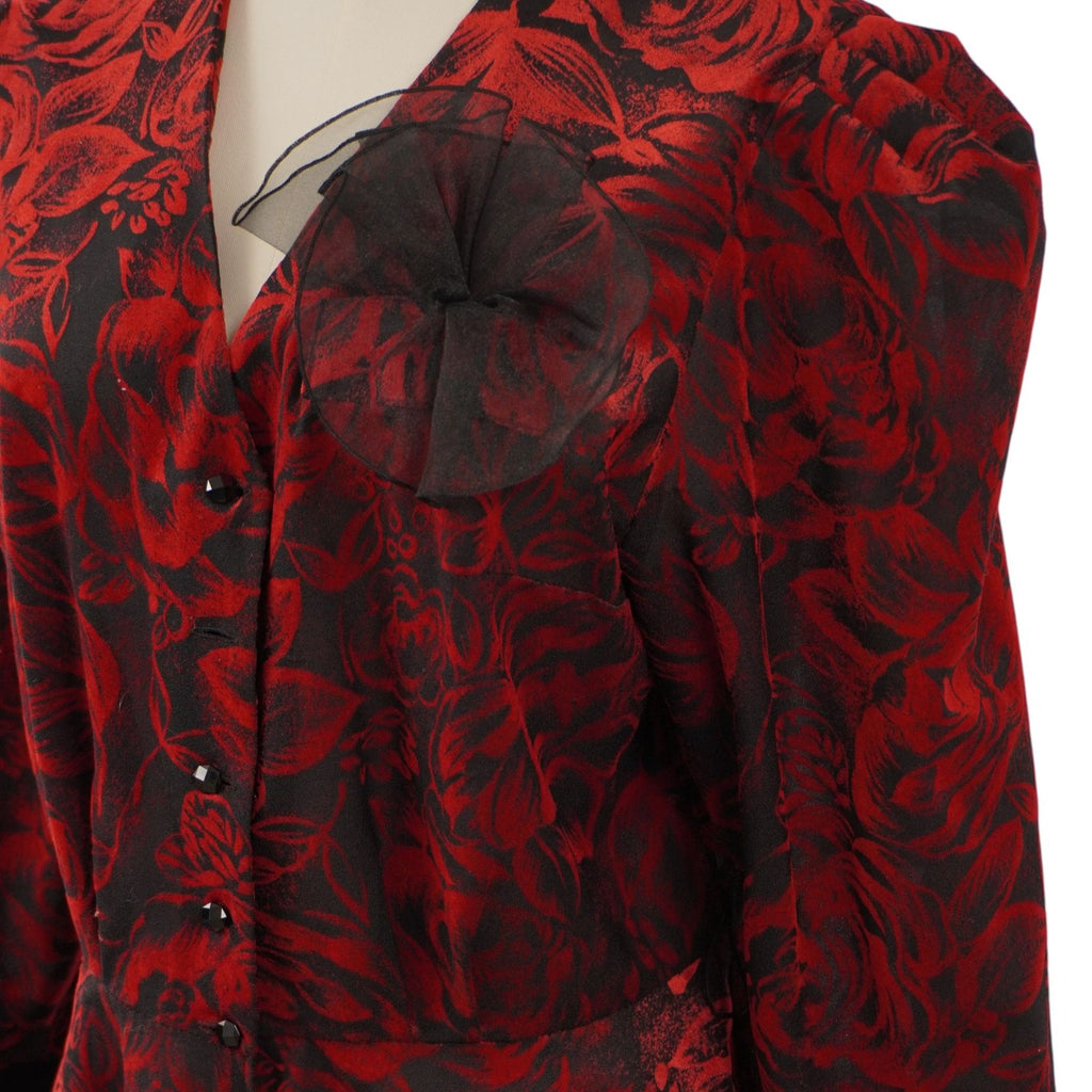 Macro dell'applicazione ornamentale in organza nera semitrasparente sul petto della blusa, sovrapposta alla fantasia a rose.
