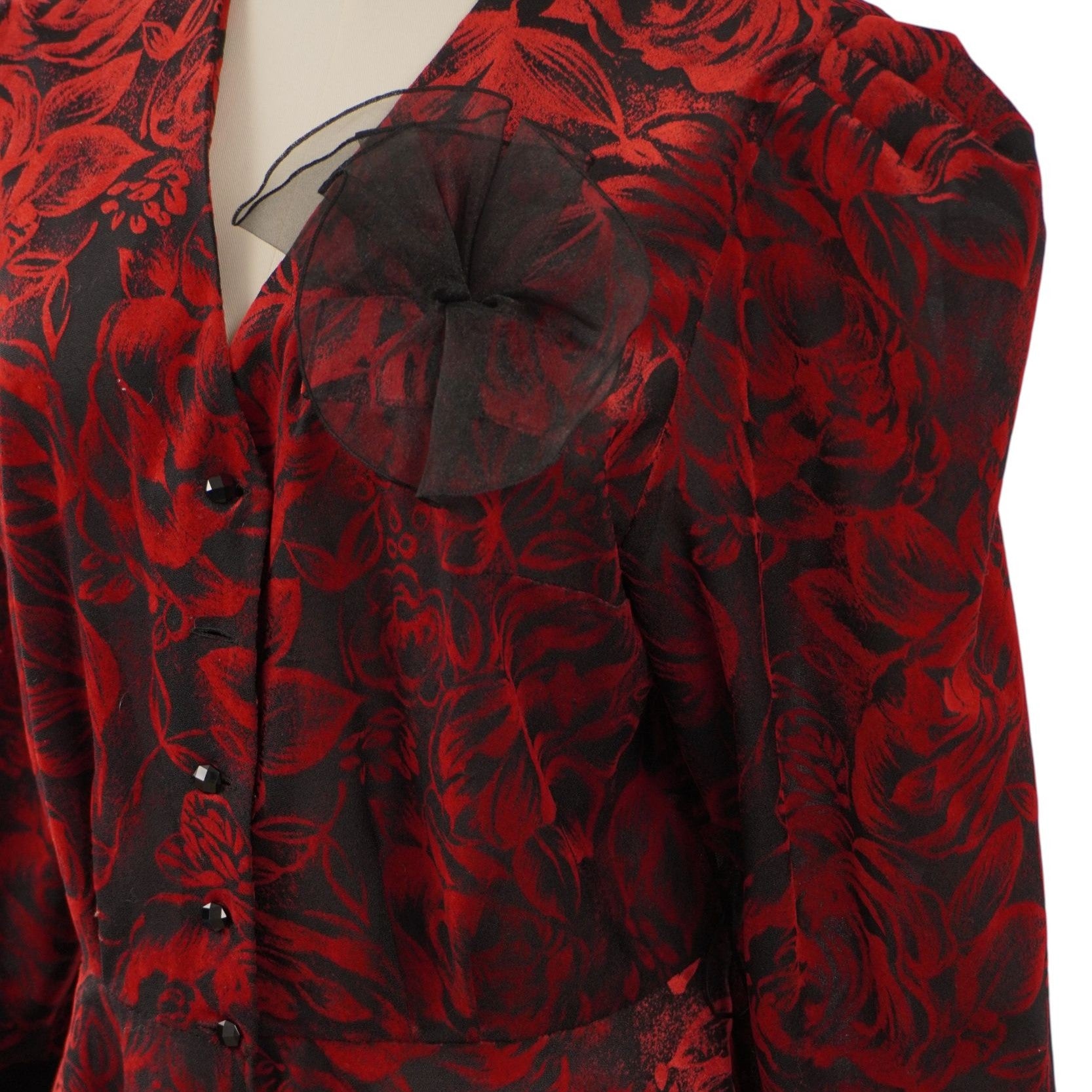 Macro dell'applicazione ornamentale in organza nera semitrasparente sul petto della blusa, sovrapposta alla fantasia a rose.