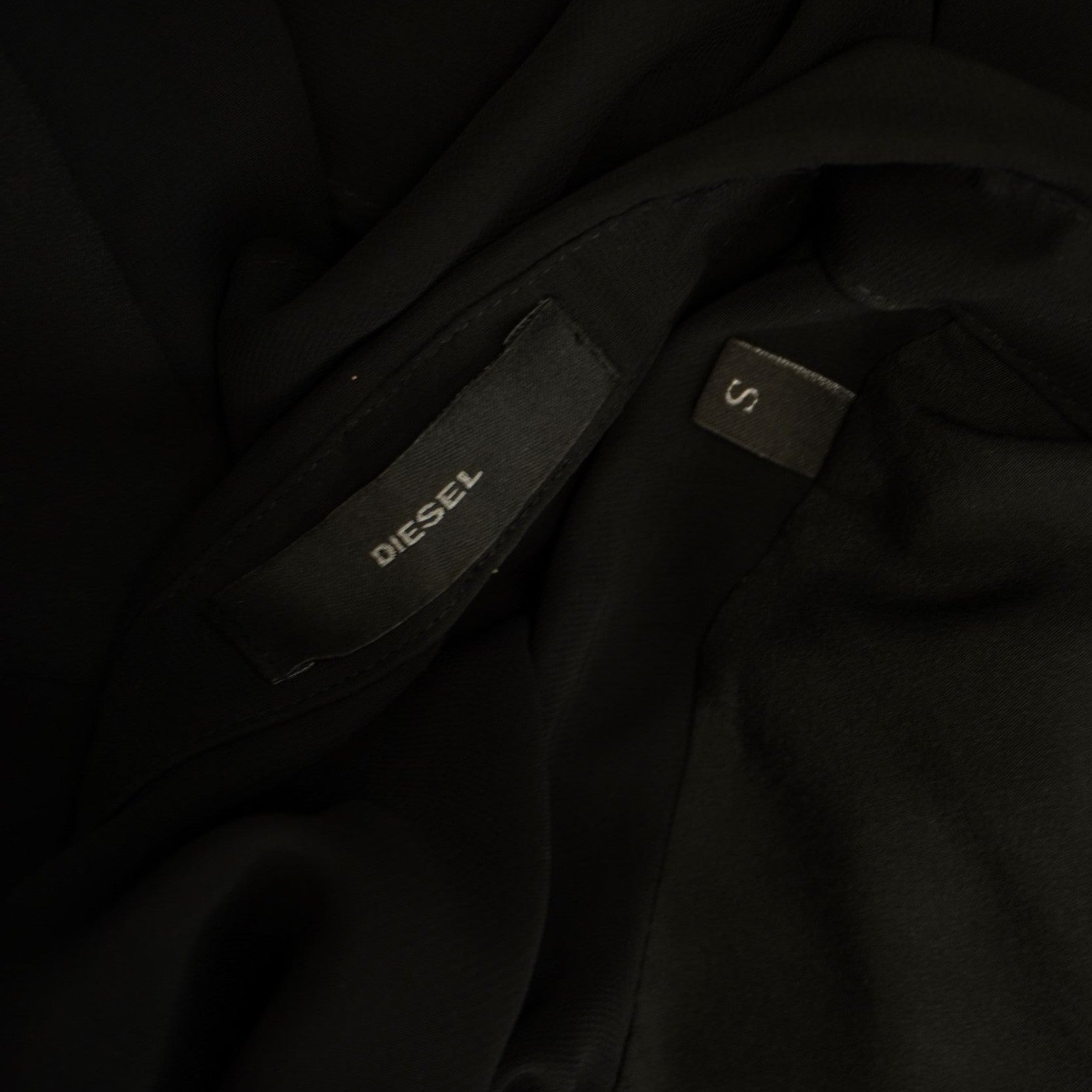 Primo piano dell'etichetta nera con logo Diesel cucita all'interno dell'abito per certificarne l'originalità.