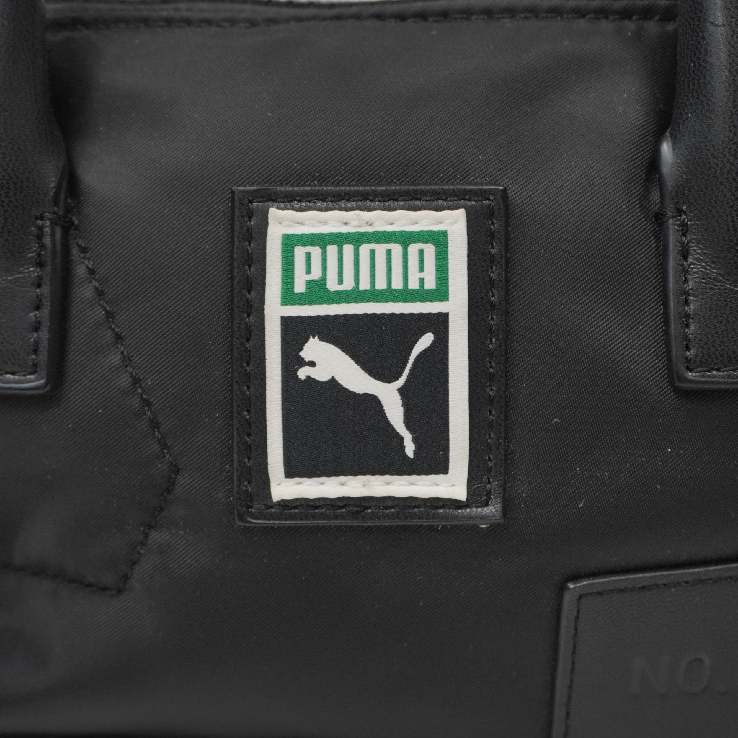  Primo piano del patch ricamato Puma Archive verde, bianco e nero applicato sulla parte frontale della borsa.