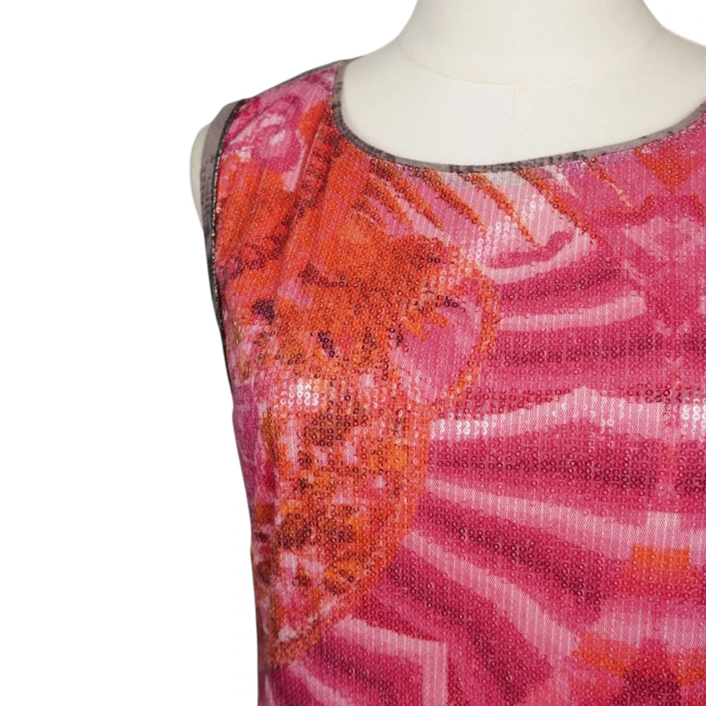 Primo piano dello scollo a girocollo e del giromanica dell'abito con profili piatti color tortora e dettaglio del tessuto fucsia ricoperto di paillettes lucide.