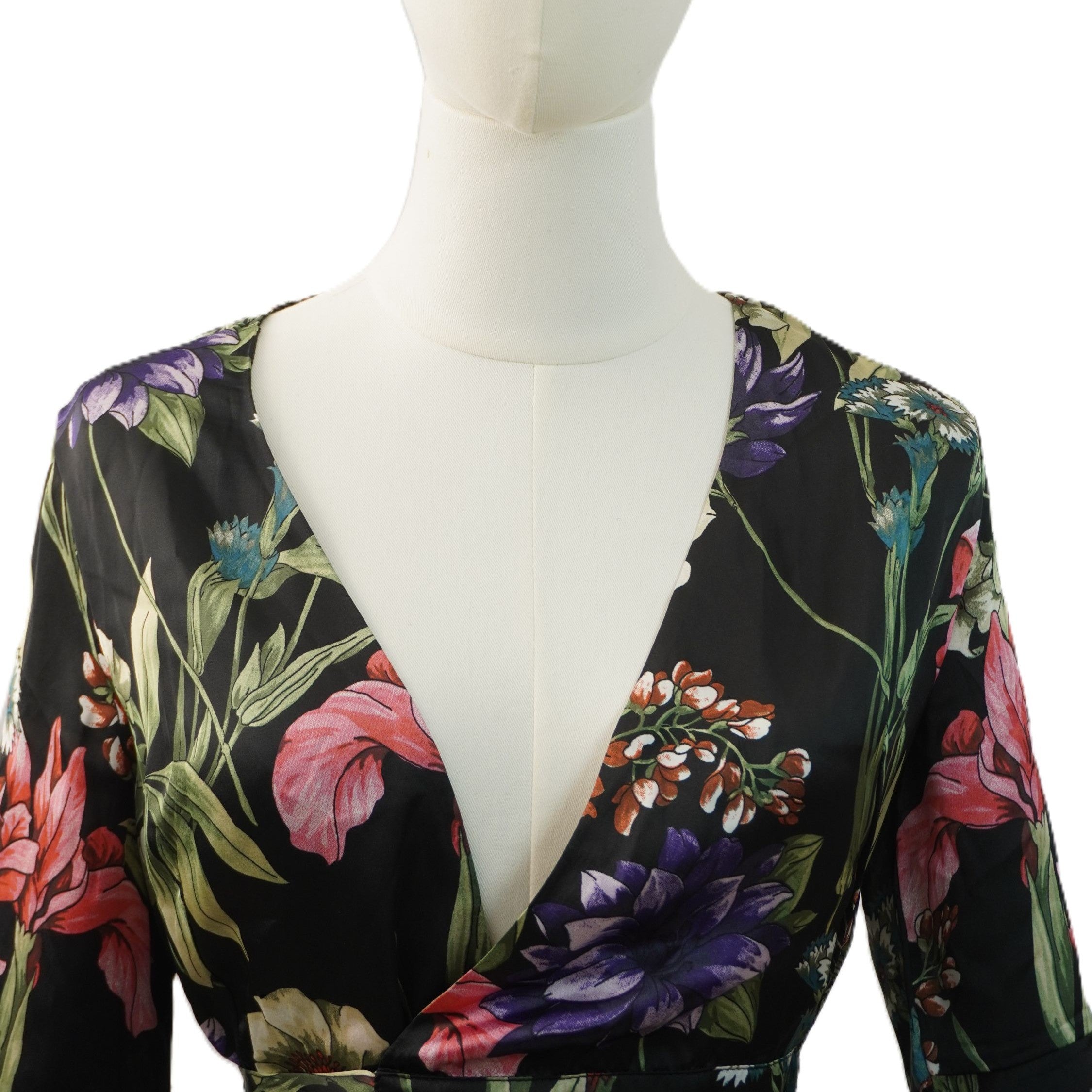 Primo piano del profondo scollo a V incrociato sul décolleté del vestito floreale Guess.