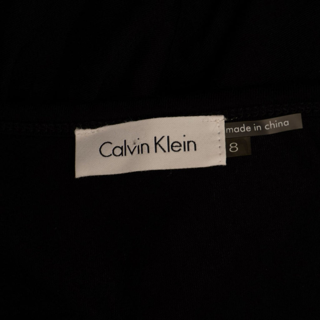 Primo piano dell'etichetta rettangolare bianca con la scritta nera Calvin Klein cucita all'interno del collo.