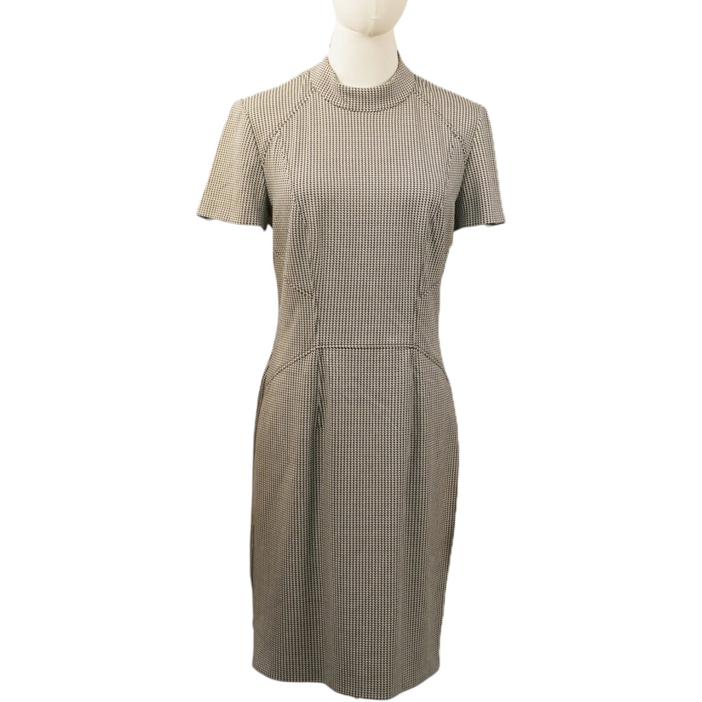 Vista frontale di un abito a tubino HUGO BOSS a motivi micro pied-de-poule bianco e nero su un manichino, con maniche corte e cuciture geometriche in vita.
