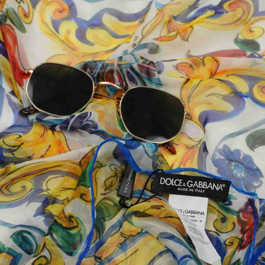  Primo piano della trama della seta Dolce & Gabbana con occhiali da sole, evidenziando i colori vibranti giallo e blu della stampa.