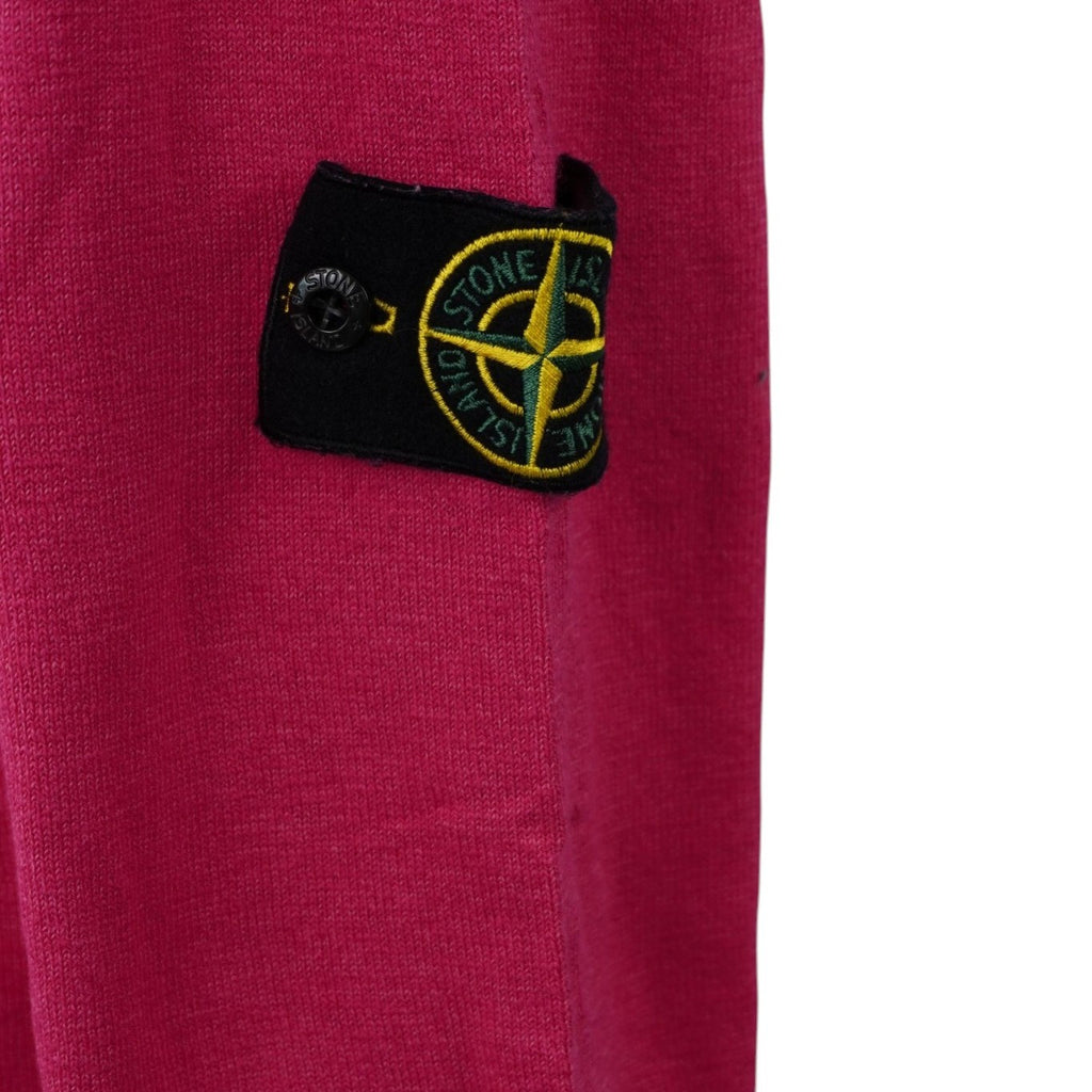 Inquadratura ravvicinata del badge rimovibile Stone Island con il logo della bussola ricamato in giallo e verde, applicato tramite due bottoni neri.