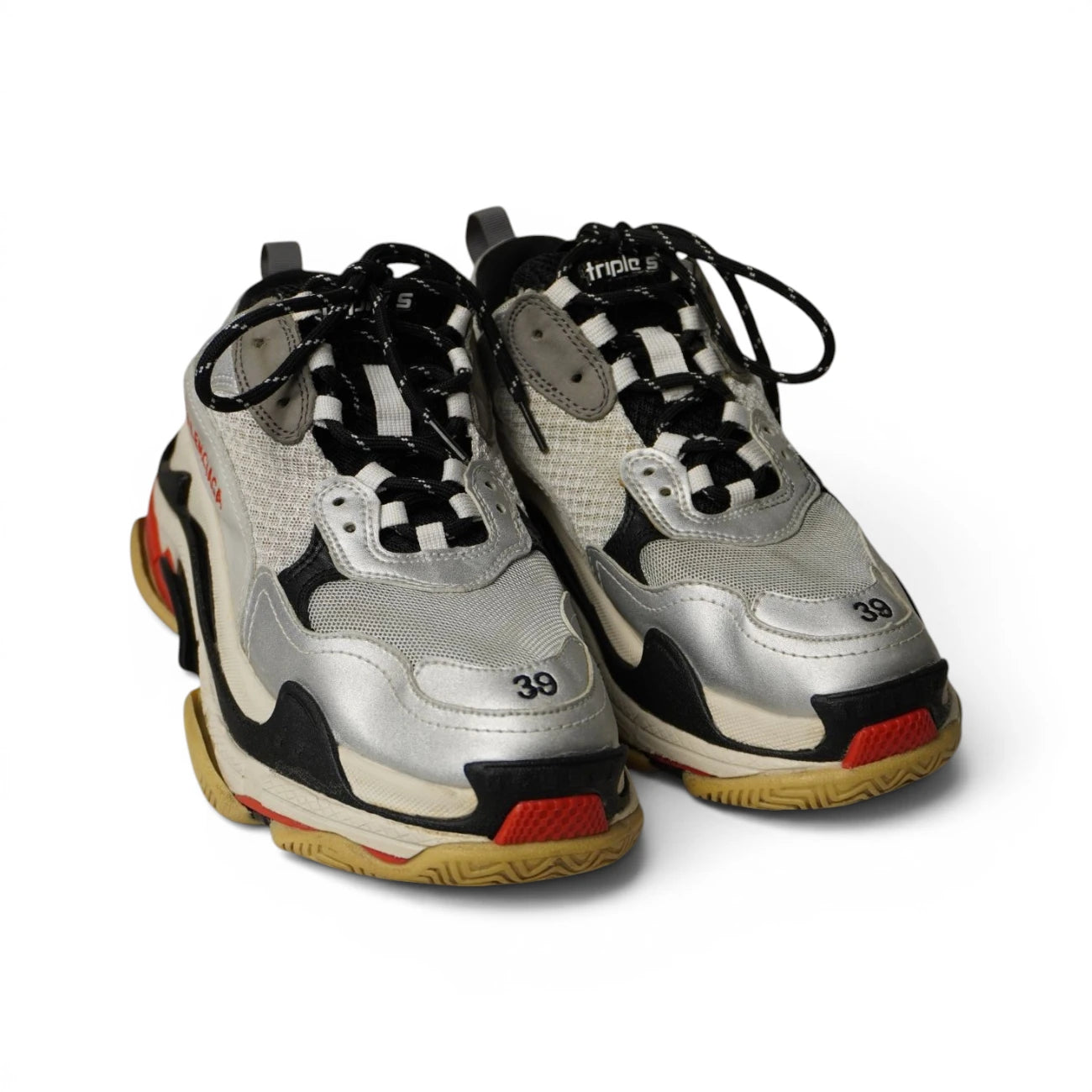 Paio di scarpe Balenciaga Triple S argento e grigie poggiate su sfondo bianco in prospettiva.