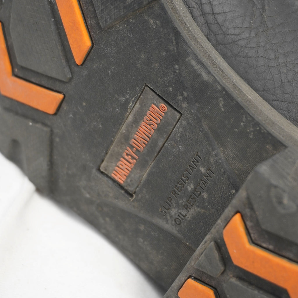 Particolare della suola in gomma tecnica con inserti arancioni e scritte slip resistant e oil resistant.