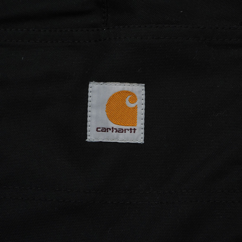 Primo piano dell'iconica etichetta quadrata in tessuto con il logo Carhartt WIP arancione e grigio cucita sulla tasca