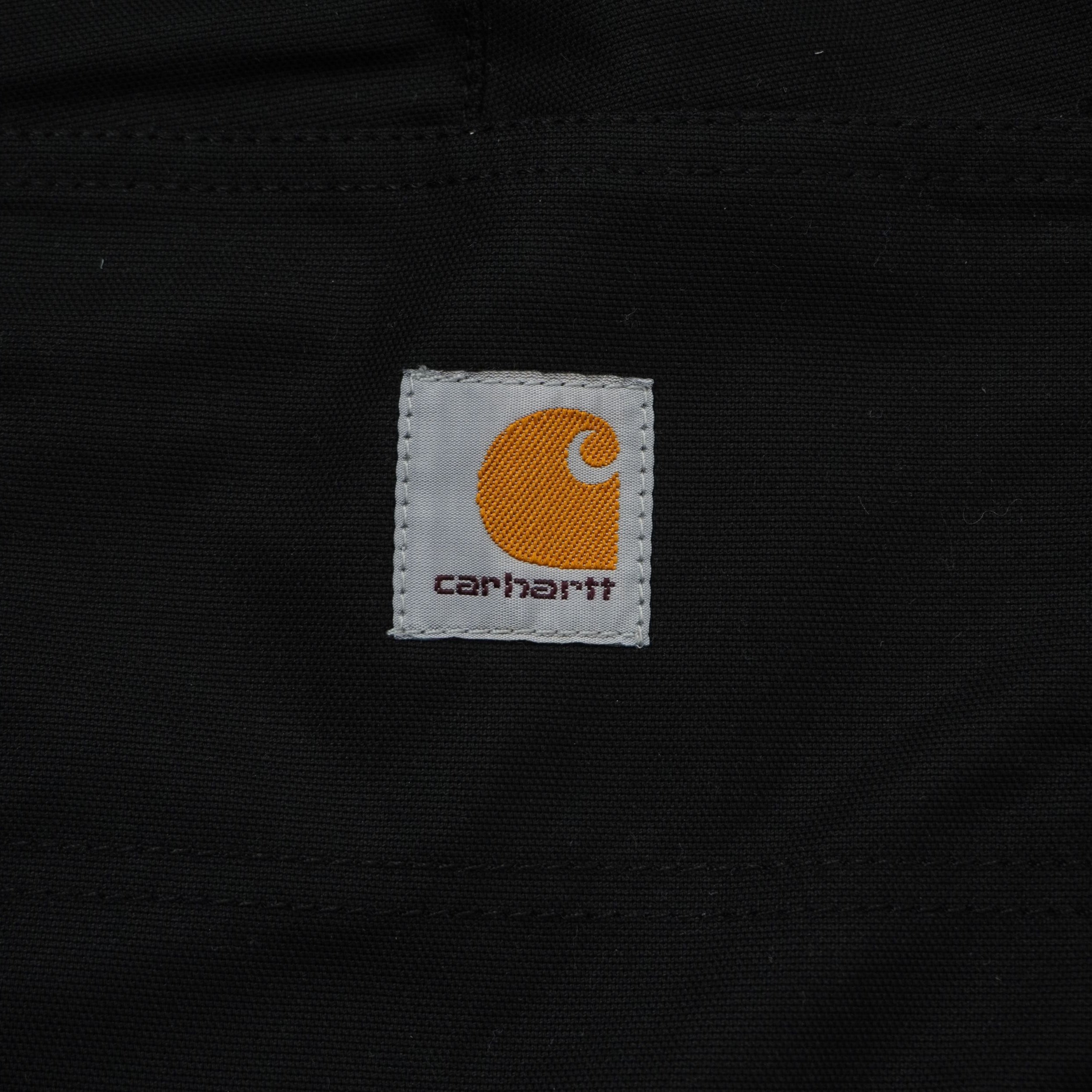Primo piano dell'iconica etichetta quadrata in tessuto con il logo Carhartt WIP arancione e grigio cucita sulla tasca