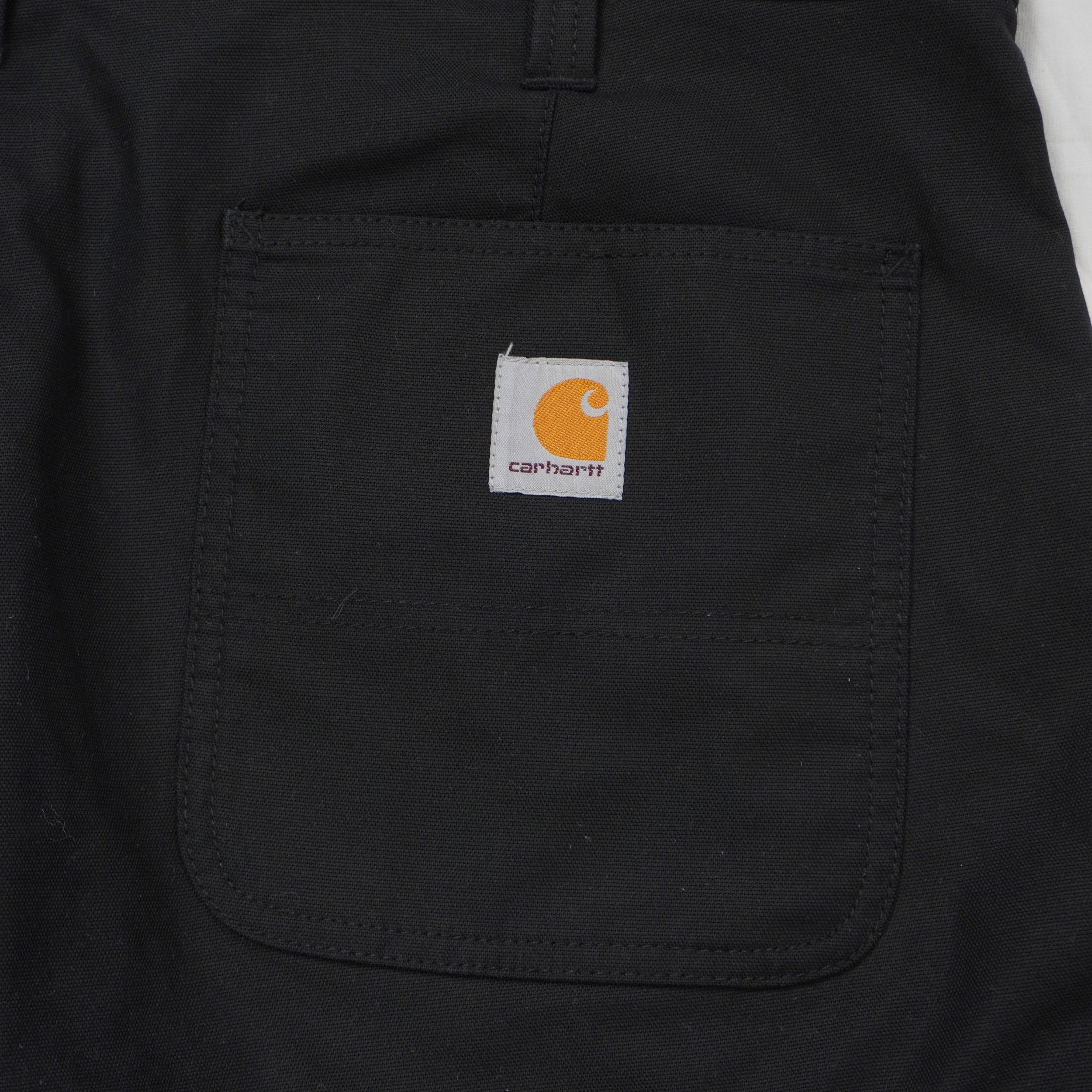 Primo piano dell'iconica etichetta quadrata in tessuto con il logo Carhartt WIP arancione e grigio cucita sulla tasca