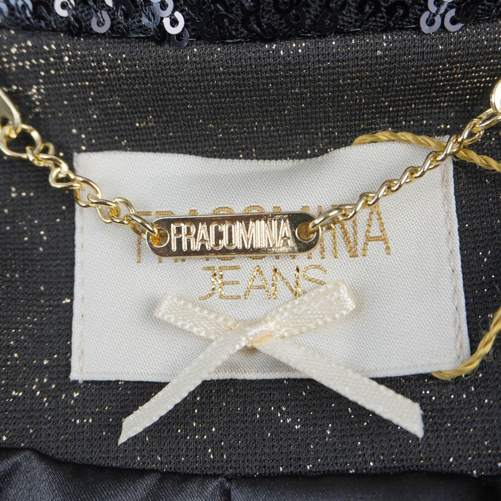 Dettaglio della targhetta dorata con logo Fracomina metallico applicata sul retro del collo con fiocchetto decorativo bianco