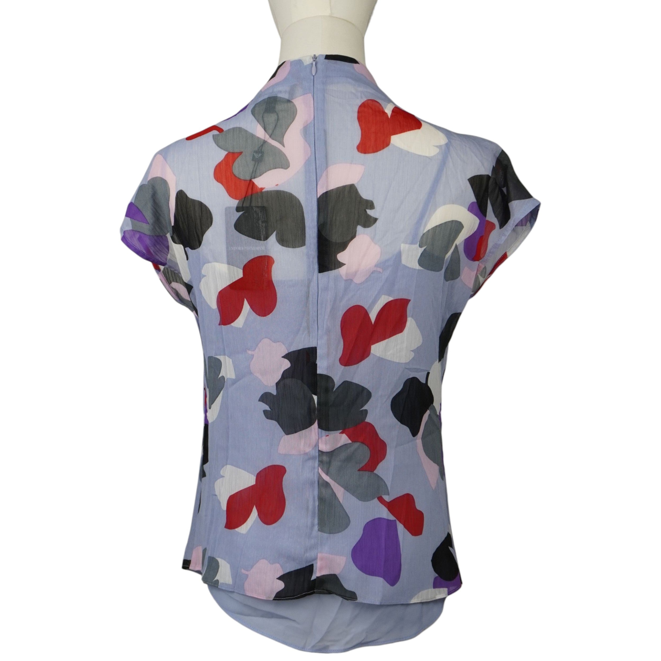 Vista posteriore della blusa lilla Emporio Armani a fantasia che mostra il taglio dritto, la stampa geometrica e la chiusura a zip sul collo.