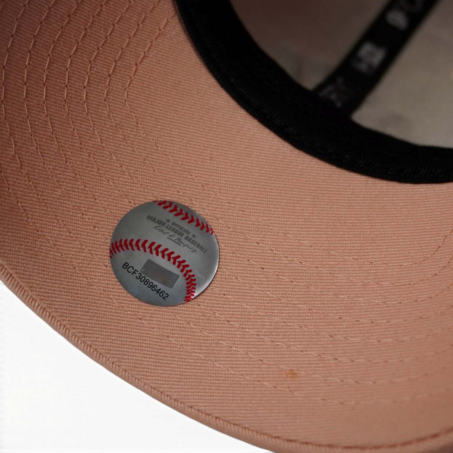 Primo piano del bollino olografico argentato e numerato della Major League Baseball applicato sotto la visiera del cappellino.