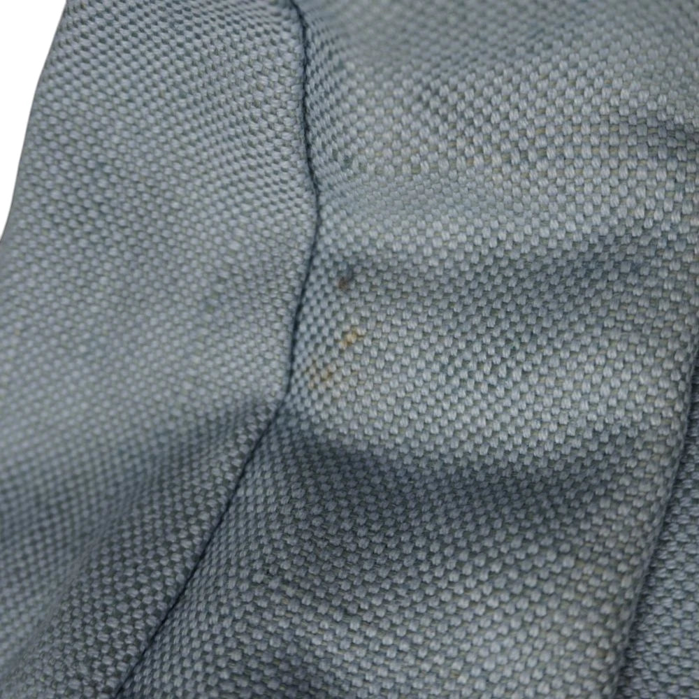  Ingrandimento macro del tessuto canvas grigio a nido d'ape che mostra una piccola macchia scura concentrata e una lieve usura superficiale.