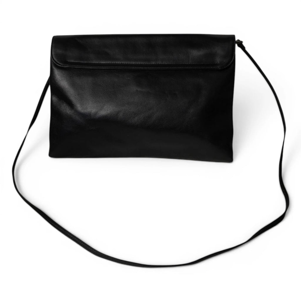 Vista d'insieme posteriore della borsa minimalista a busta firmata Krizia con la sottile tracolla in pelle nera distesa.