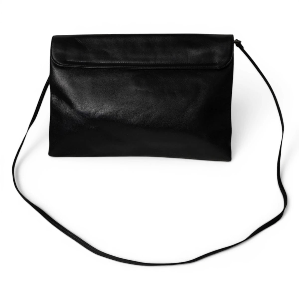 Vista d'insieme posteriore della borsa minimalista a busta firmata Krizia con la sottile tracolla in pelle nera distesa.