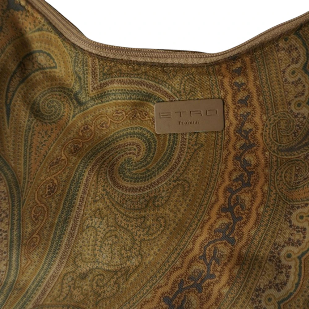 Primo piano della targhetta rettangolare marrone con l'incisione ufficiale del brand Etro Profumi applicata sul tessuto jacquard.