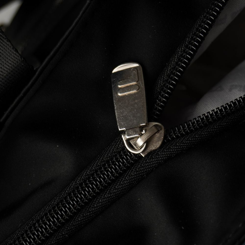  Primo piano della chiusura lampo superiore della borsa con tiralampo rettangolare in metallo argentato con inciso il logo F-Box di FILA.