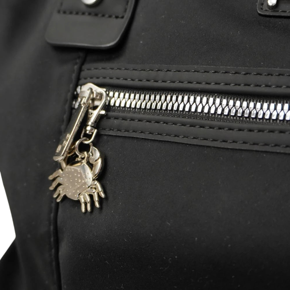 Dettaglio ravvicinato del ciondolo charm metallico silver a forma di granchio tridimensionale attaccato alla cerniera frontale della borsa.