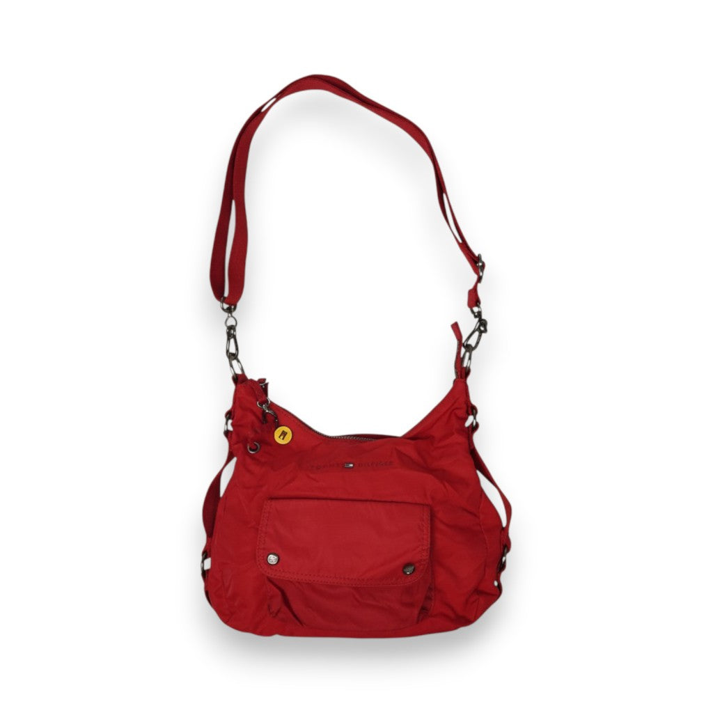Vista frontale intera della borsa a spalla Tommy Hilfiger in nylon rosso, con tasca anteriore, tracolla regolabile e charm giallo lucido.