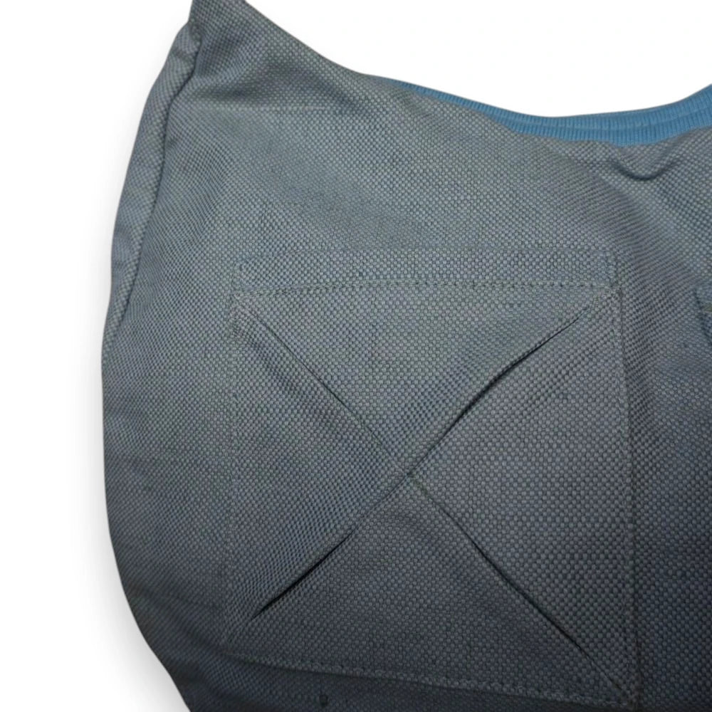 Primo piano ravvicinato della tasca esterna applicata sulla borsa grigia, caratterizzata da una vistosa cucitura geometrica di rinforzo a forma di X.