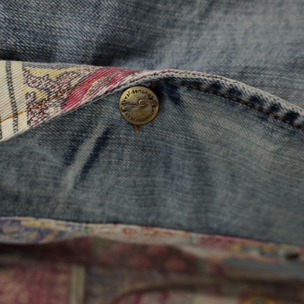 Dettaglio macro del bottone metallico originale inciso con stemma araldico e logo Gattinoni Jeans
