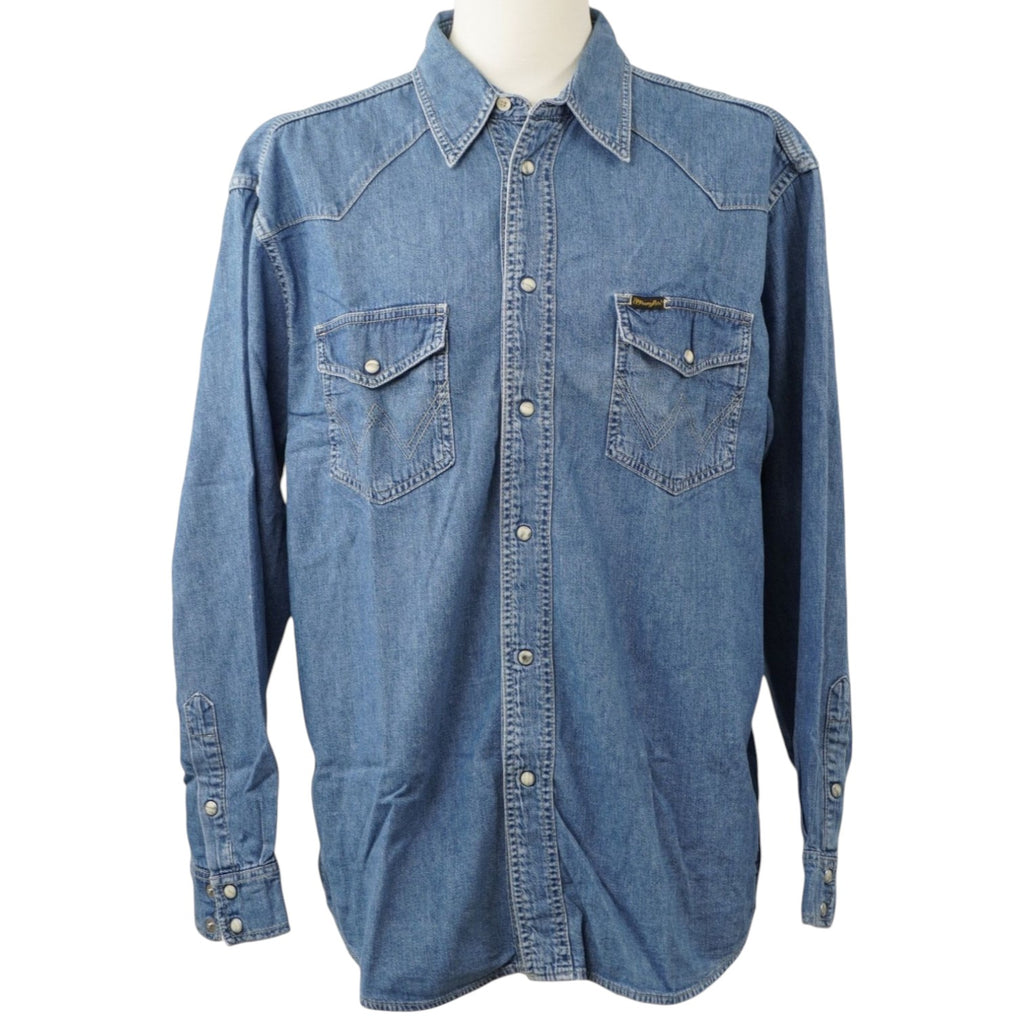 Vista frontale su manichino di una camicia di jeans azzurra Wrangler Authentic Western a maniche lunghe, con tasche sul petto e bottoni automatici.