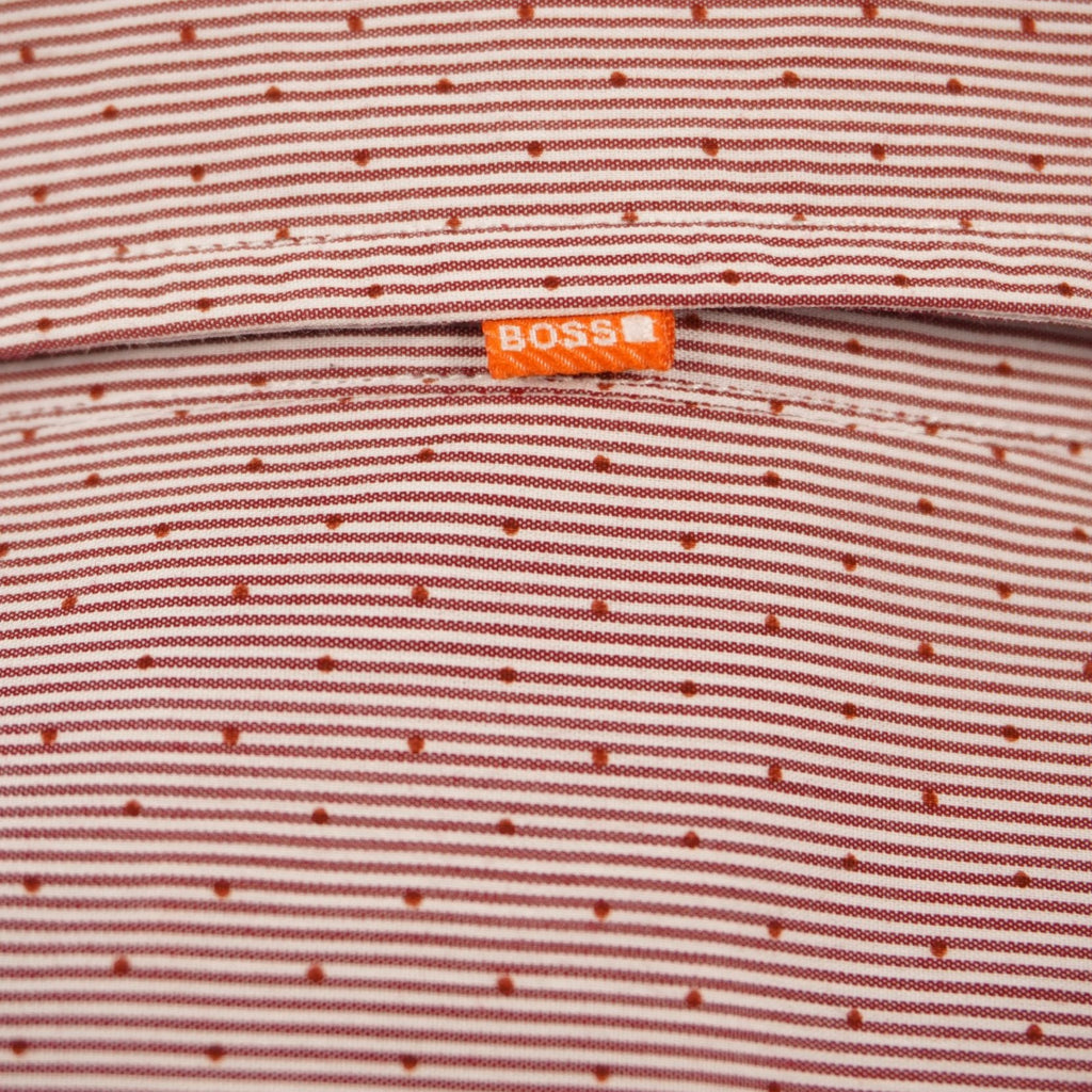 Dettaglio della micro-trama del tessuto dobby rosso Hugo Boss con focus sulla piccola asola e sulla fettuccia arancione sul retro.