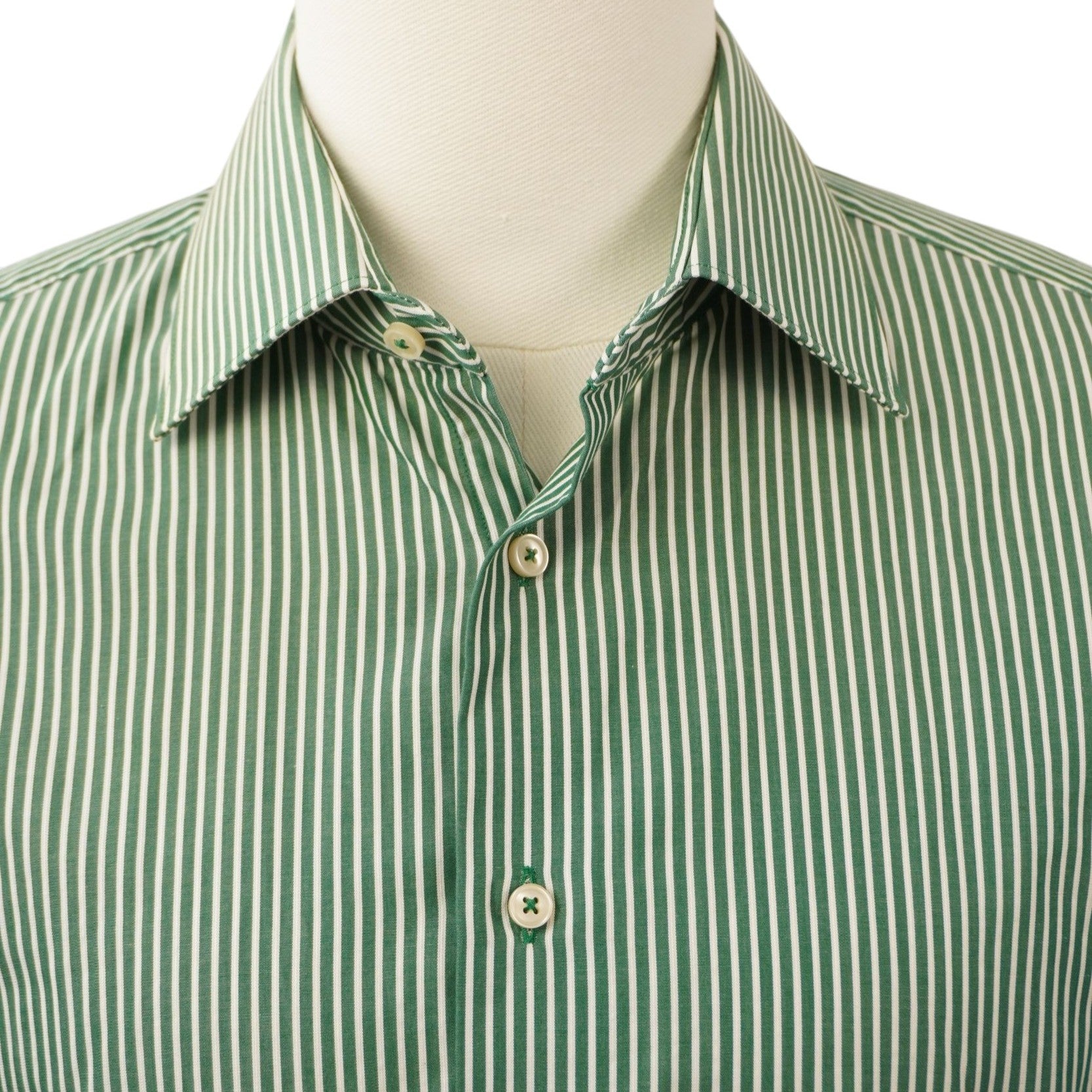 Primo piano del colletto classico e dei primi bottoni della camicia a micro-righe verticali bianche e verdi.