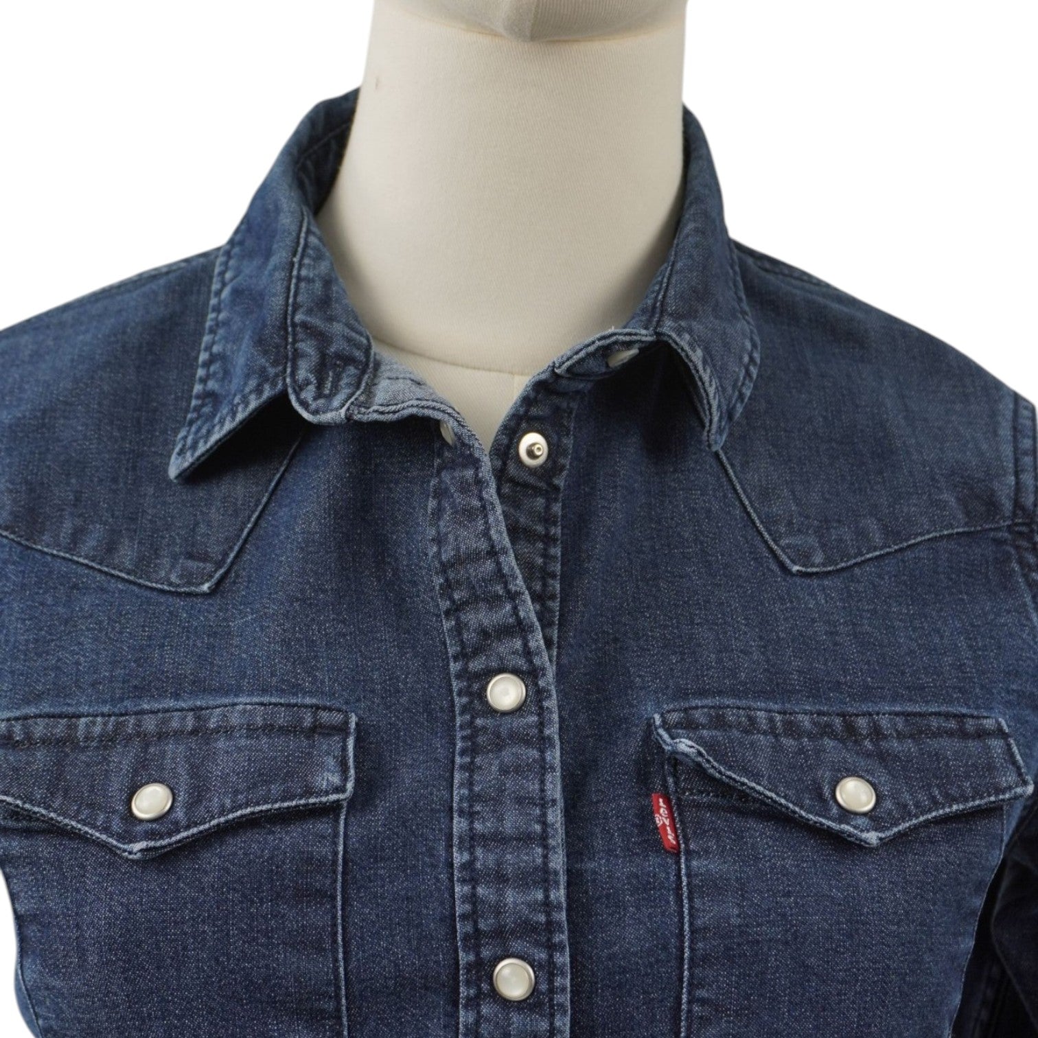 Inquadratura ravvicinata del colletto a punta e della parte superiore della camicia in denim scuro Levi's.