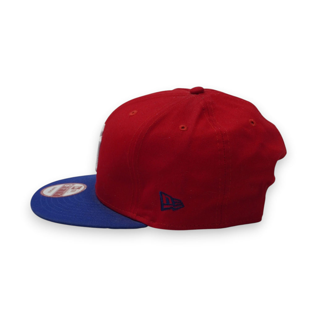 Profilo laterale sinistro del cappellino New York Yankees rosso e blu che mostra la struttura della corona alta e la visiera piatta.