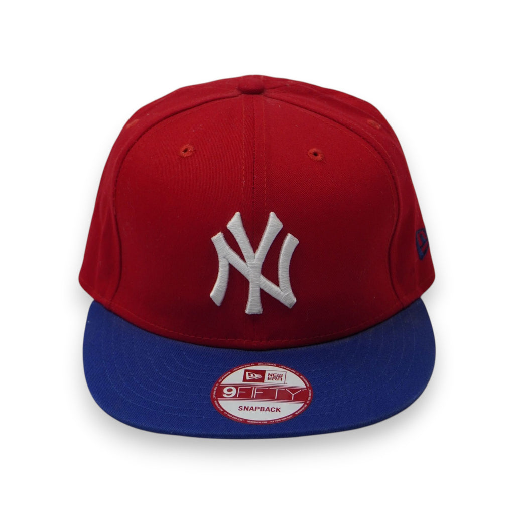 Cappellino New Era 9FIFTY Snapback dei New York Yankees bicolore con corona rossa, visiera piatta blu e logo NY bianco ricamato sul davanti.