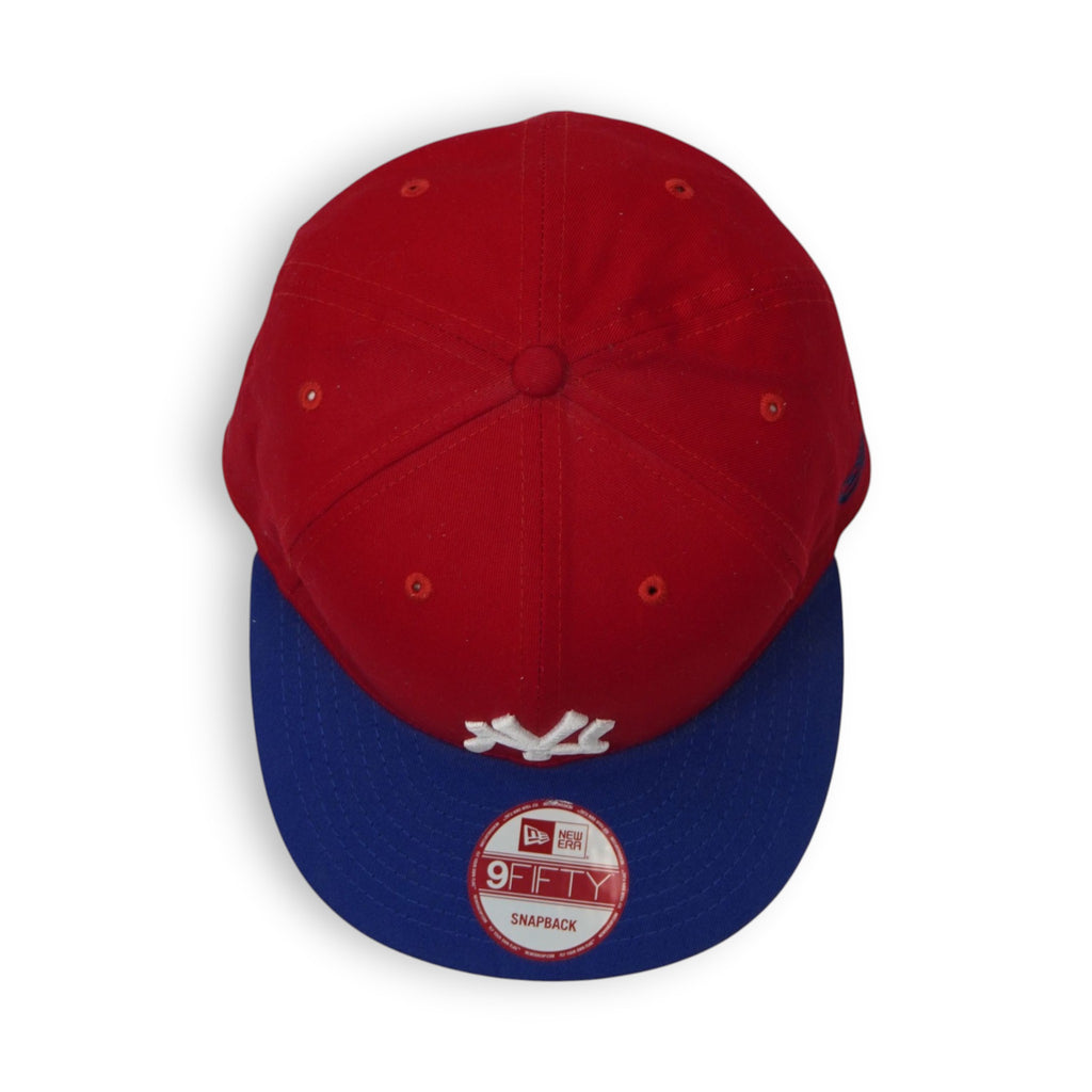 Vista dall'alto zenitale del cappellino New Era 9FIFTY con struttura geometrica a sei pannelli rossi e bottone superiore.