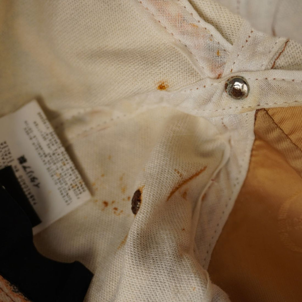  Primo piano della parte interna del cappello che mostra aloni di ruggine e segni di usura sulla fodera bianca.