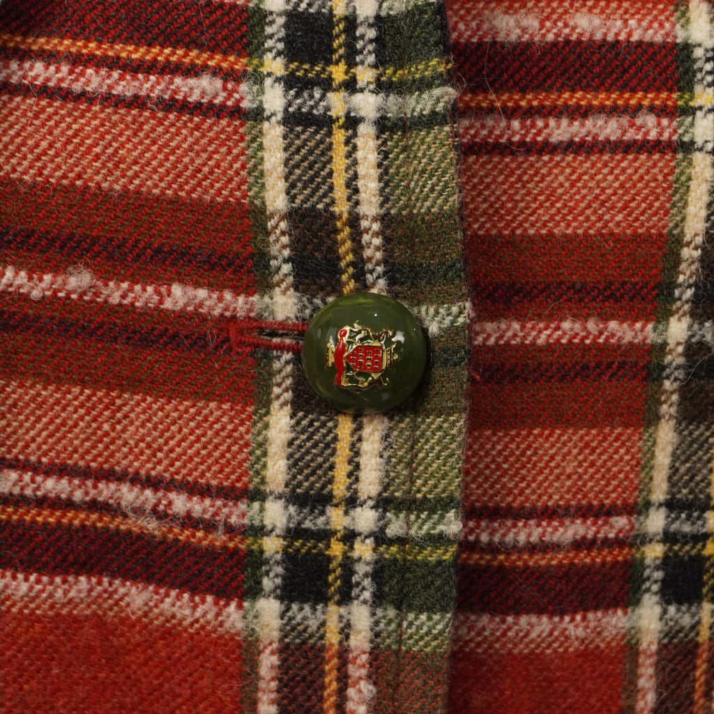 Dettaglio ravvicinato di uno dei bottoni rotondi decorativi colorati cuciti sulla chiusura frontale del cappotto tartan.