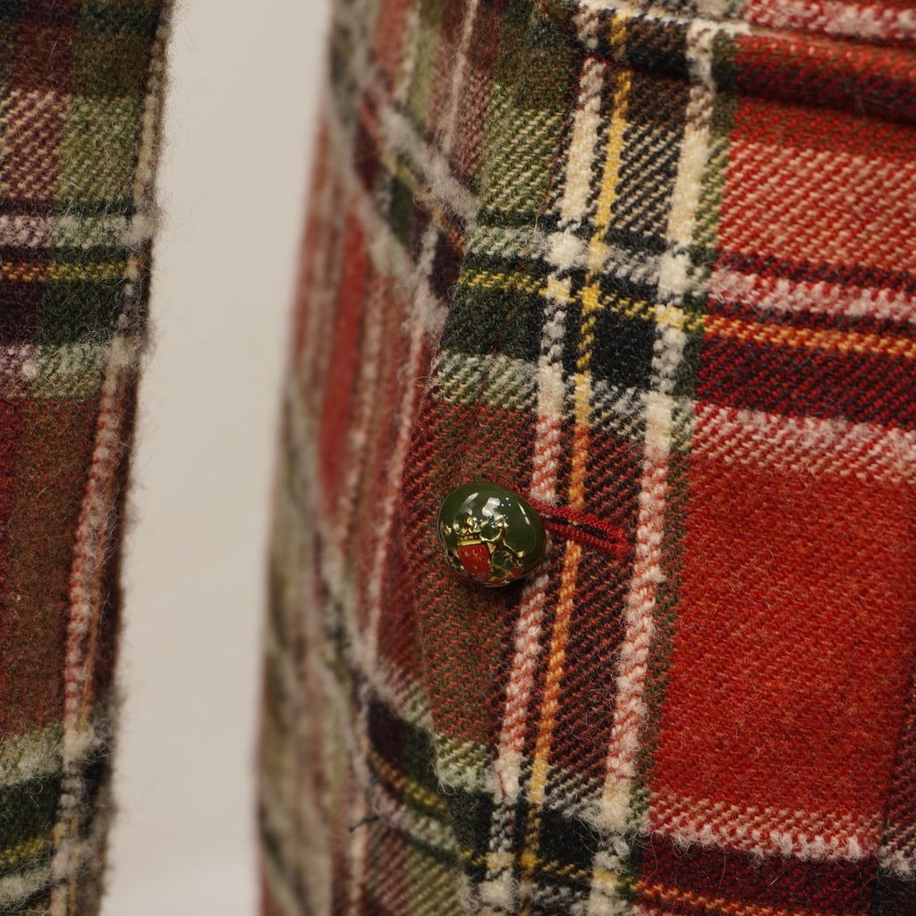  Primo piano della tasca laterale con bottone verde a contrasto inserita nel motivo a quadri del cappotto vintage.