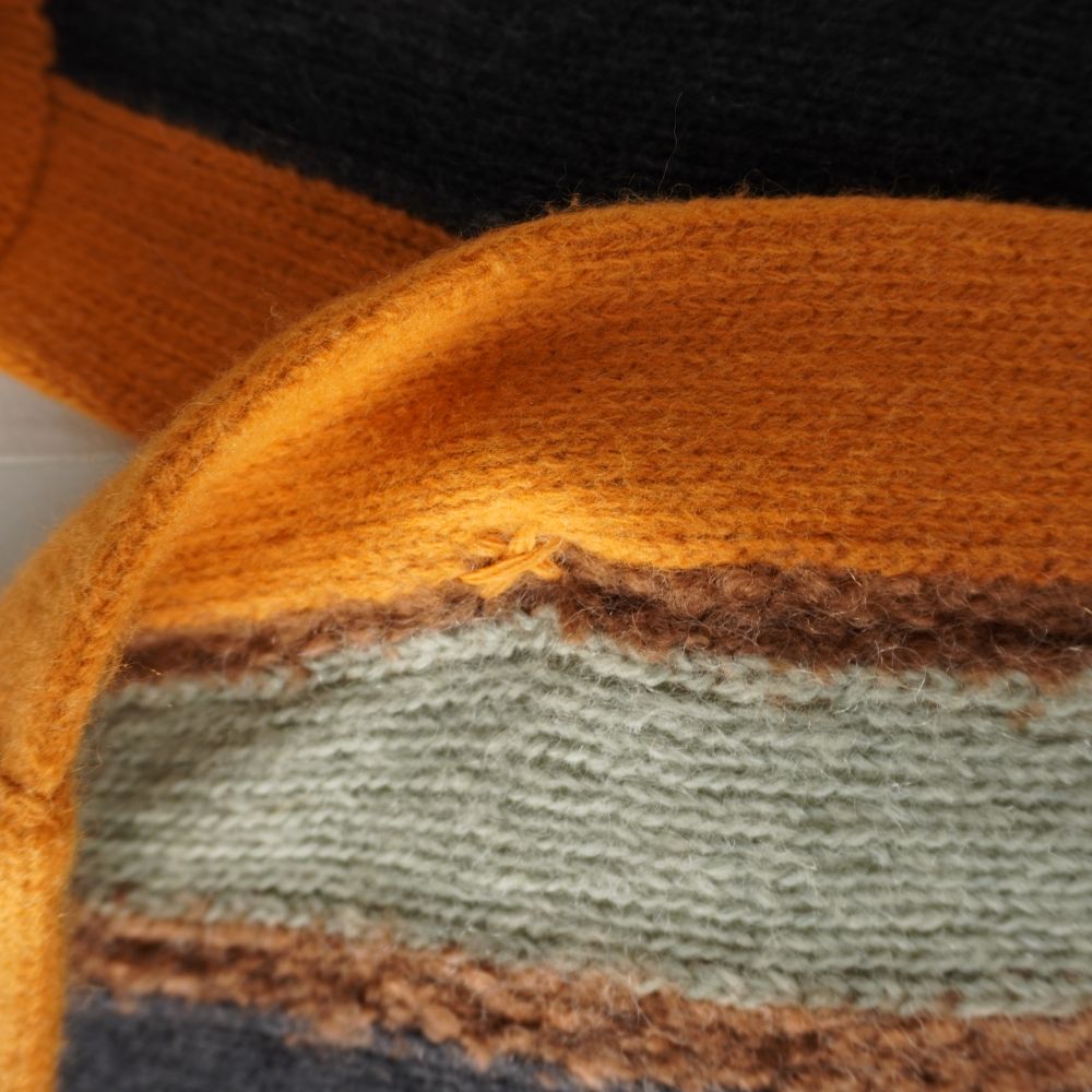 Primo piano del tessuto in maglia del cardigan Missoni con punto di cucitura di rinforzo sul bordo arancione e marrone.