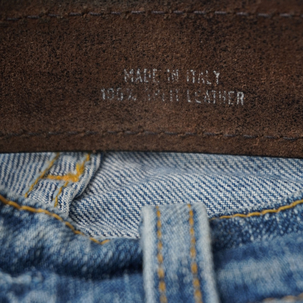Vista ravvicinata delle scritte argentate Made in Italy e 100% Split Leather incise sul retro della cintura.