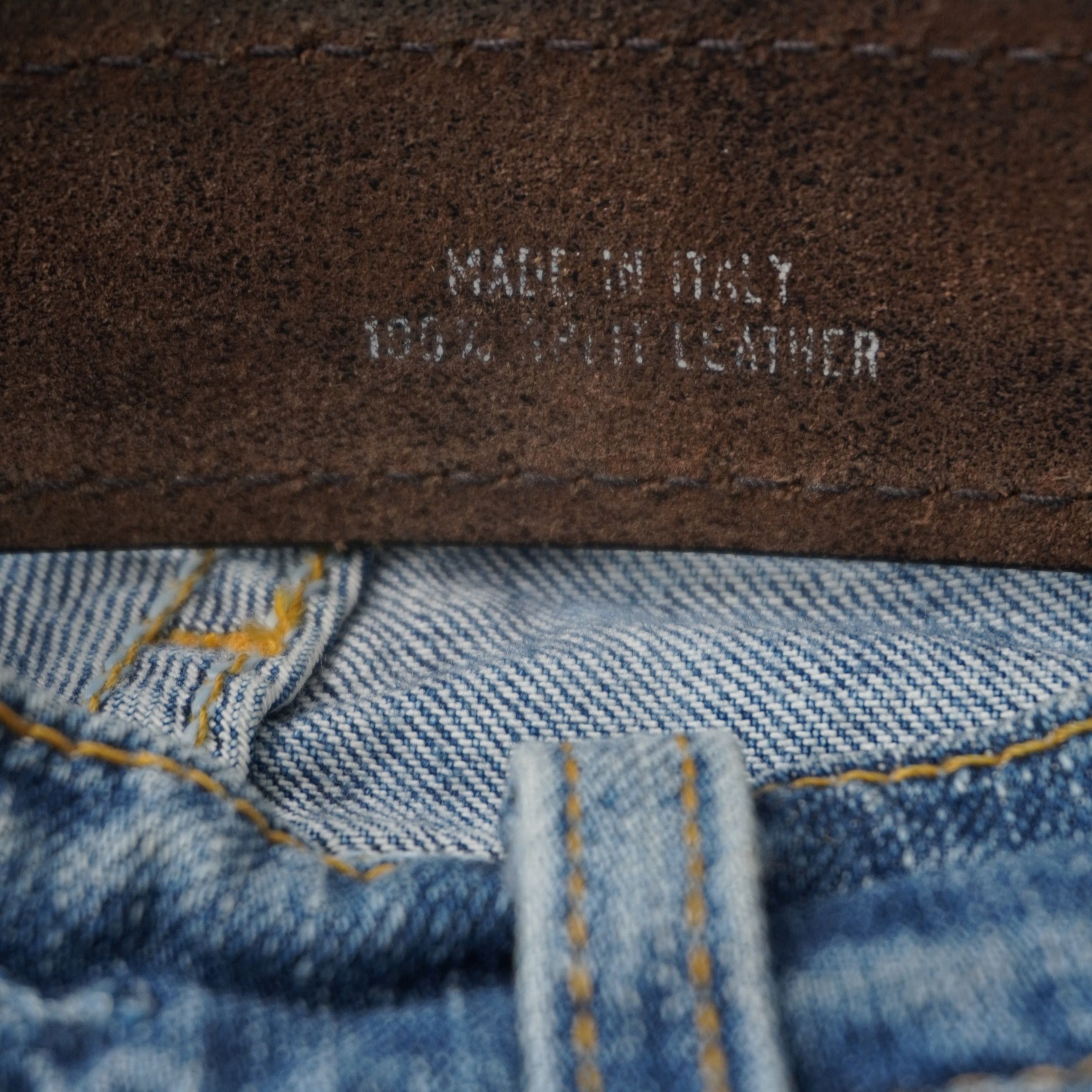 Vista ravvicinata delle scritte argentate Made in Italy e 100% Split Leather incise sul retro della cintura.