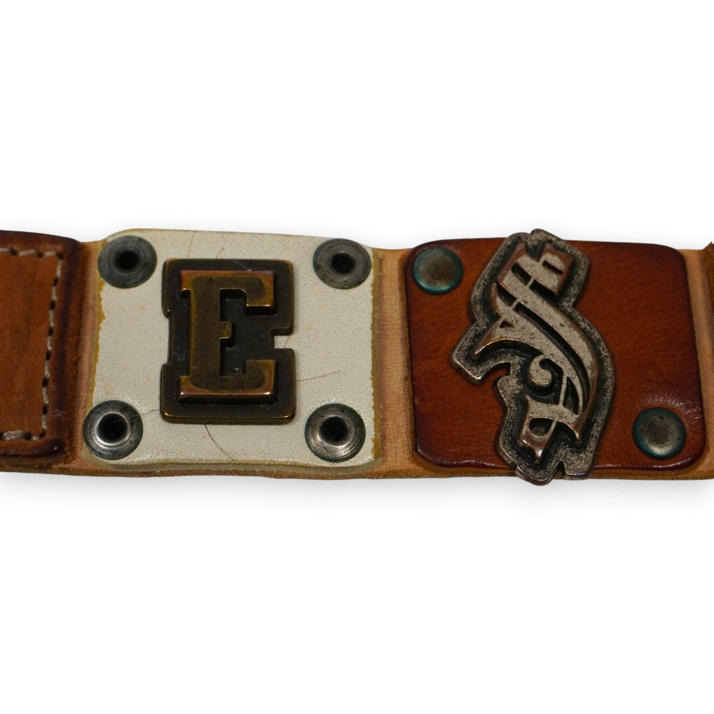 Primo piano delle lettere metalliche decorative E e S fissate su inserti di pelle della cintura Diesel d'archivio.