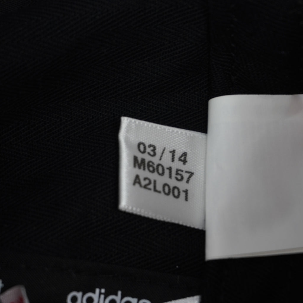 Macro del piccolo tag bianco Adidas con data di produzione 03/14 e codice articolo d'archivio M60157.