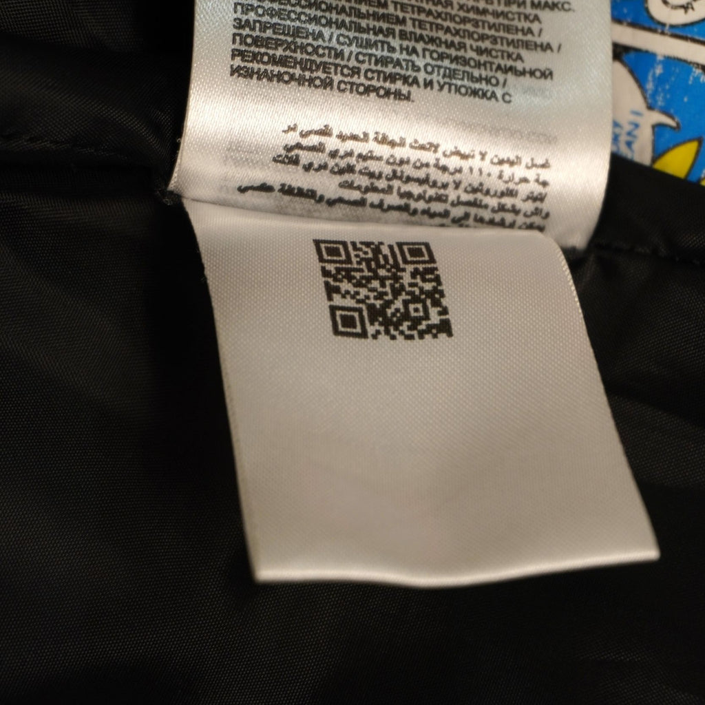 Dettaglio dell'etichetta interna di autenticità dotata di codice QR e codice alfanumerico per la verifica dell'originalità del prodotto Moncler.