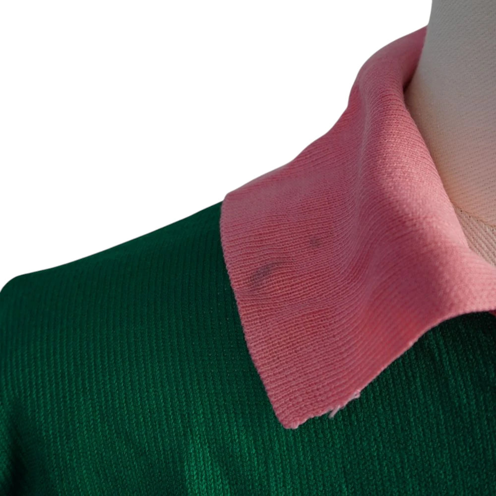 Foto di dettaglio del colletto in maglia rosa che mostra una piccola macchia scura superficiale