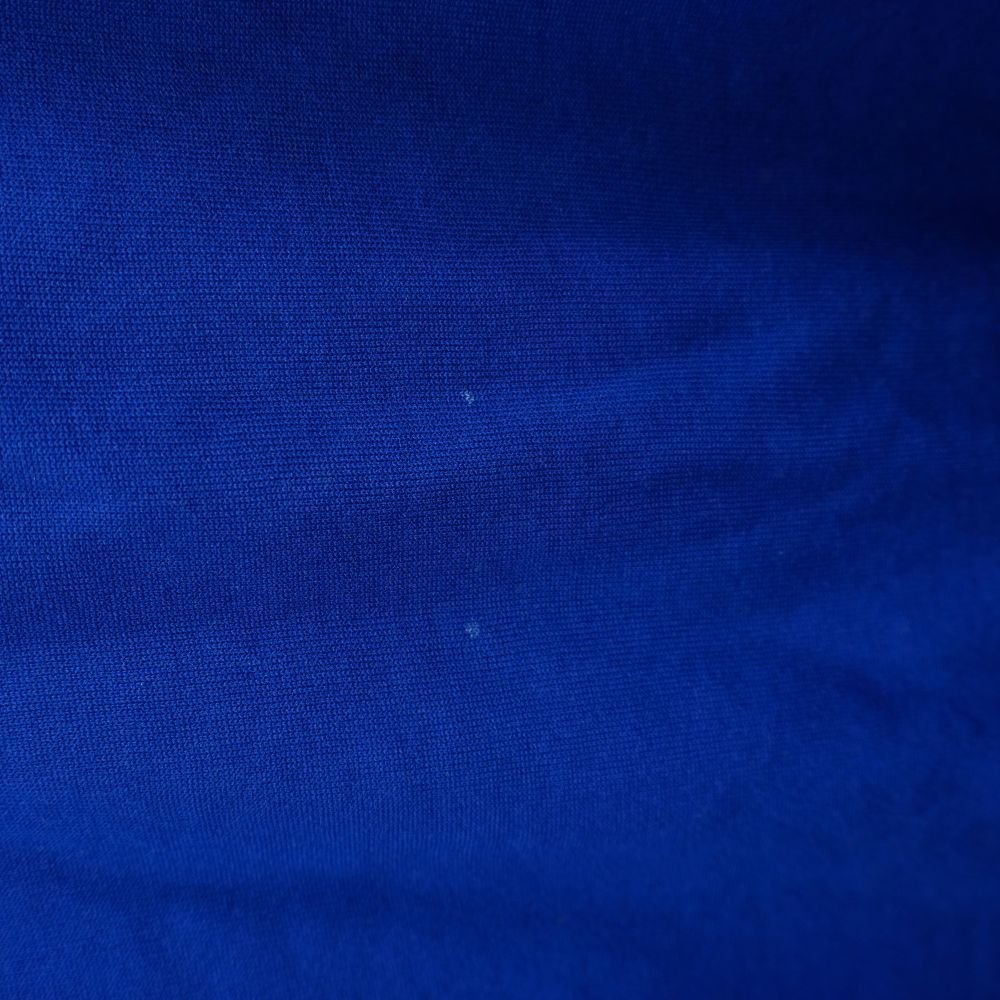 Foto macro del tessuto azzurro che mostra due piccoli e lievi puntini chiari superficiali
