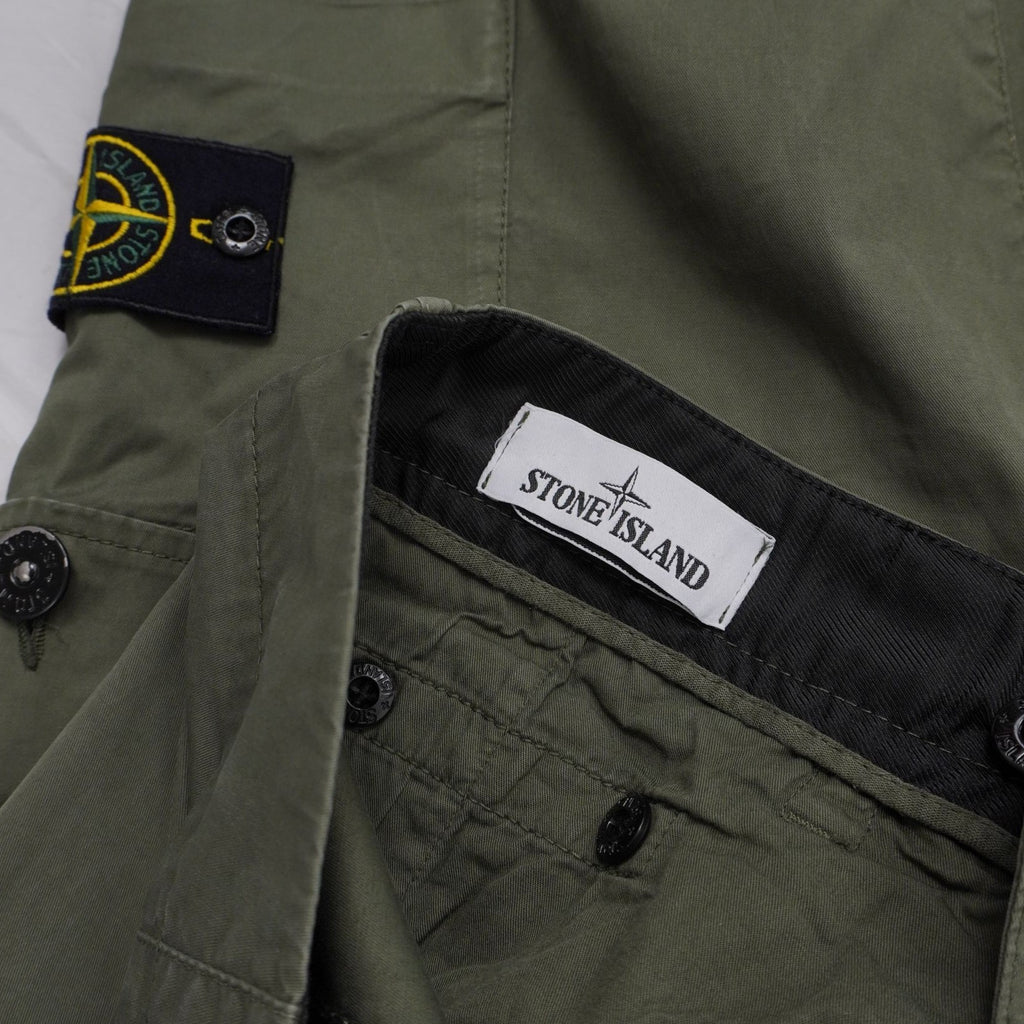 Inquadratura ravvicinata del badge rimovibile Stone Island applicato sulla tasca laterale e dell'etichetta interna del brand.