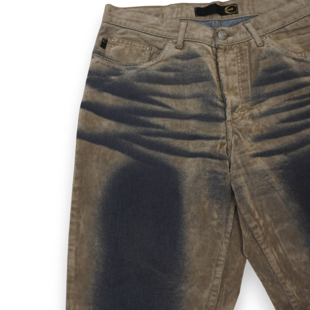 Primo piano del bacino dei jeans Just Cavalli che mostra profonde baffature tridimensionali e sfumature scure ad aerografo su base tortora.